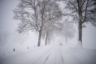 Schneefälle — © Ein Auto fährt über eine Schnee verwehte Landstraße. Foto: Lino Mirgeler