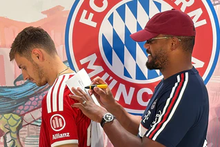 Trainer Vincent Kompany (r) malt - und Josip Stanisic muss raten. — © Christian Kunz/dpa