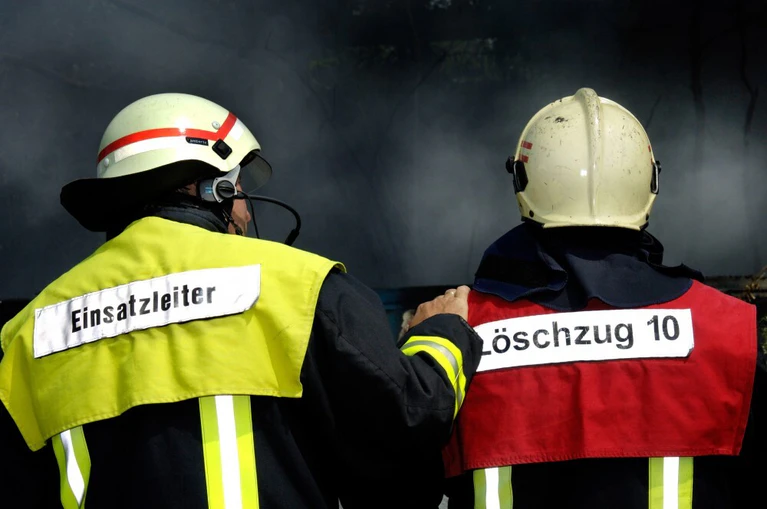  — © Feuerwehrleute im Einsatz. Einsatzleiter muntert einen erschöpften Kameraden auf.