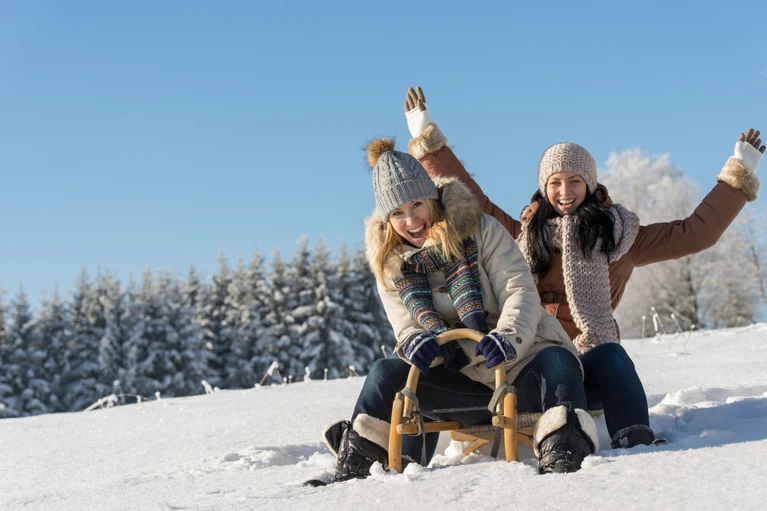 Winter — © Two girlfriends sledge downhill in sunny wintertime snow wooden sledge