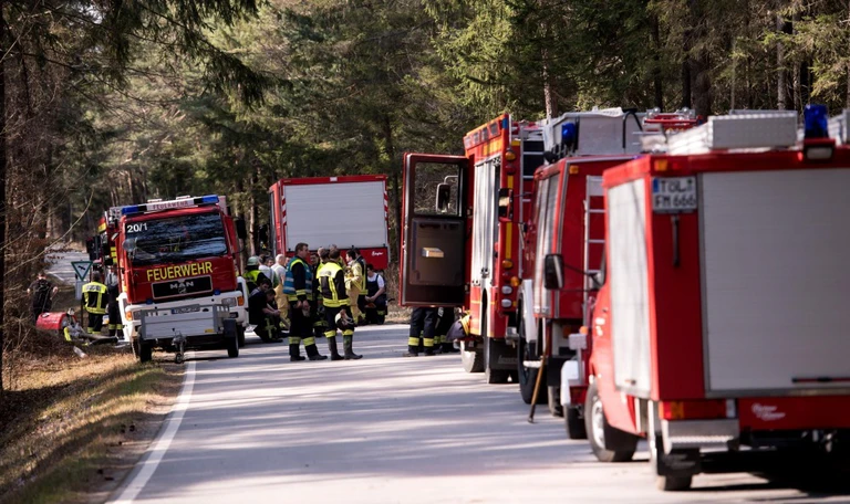 Waldbrände — © Einsatzkräfte der Feuerwehr stehen auf einer Straße in einem Waldstück. Foto: Sven Hoppe/Archiv