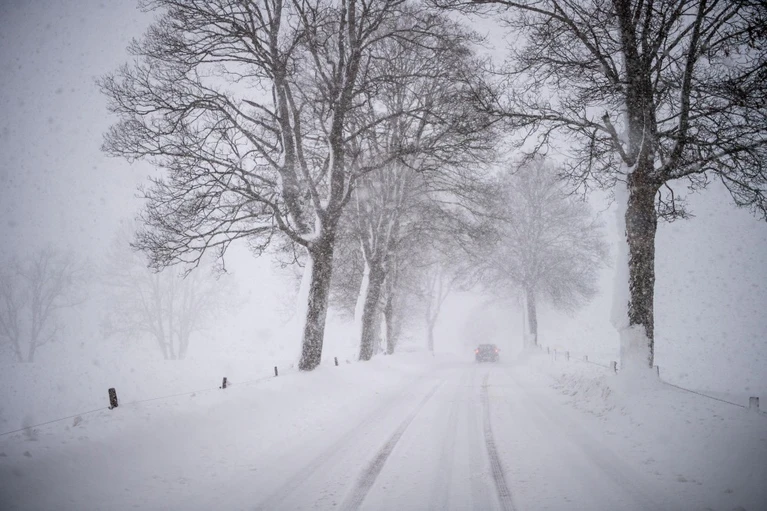 Schneefälle — © Ein Auto fährt über eine Schnee verwehte Landstraße. Foto: Lino Mirgeler