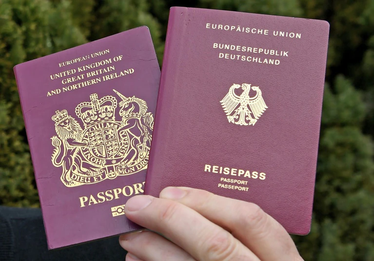 Brexit, Einbürgerung — © Ein&nbsp;Mann hält einen britischen und einen deutschen Reisepass in den Händen. Foto: Holger Hollemann/Archiv