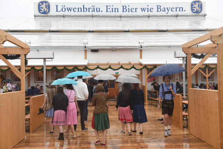 Löwenbräuzelt, Wiesnzelt — © Gäste mit Regenschirmen gehen in München (Bayern) auf dem Oktoberfest in das Löwenbräuzelt. Foto: Felix Hörhager/Archiv