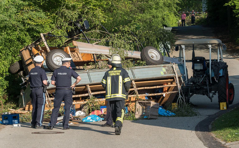  — © Polizisten und ein Feuerwehrmann vor zwei umgestürzten Traktoranhängern. Foto: Stefan Roßmann