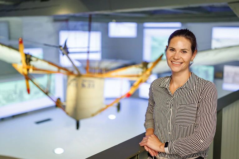 Museumsleiterin Laura Gebauer vor dem Nachbau des vielleicht ersten Motorflugzeugs der Welt. — © Daniel Karmann/dpa
