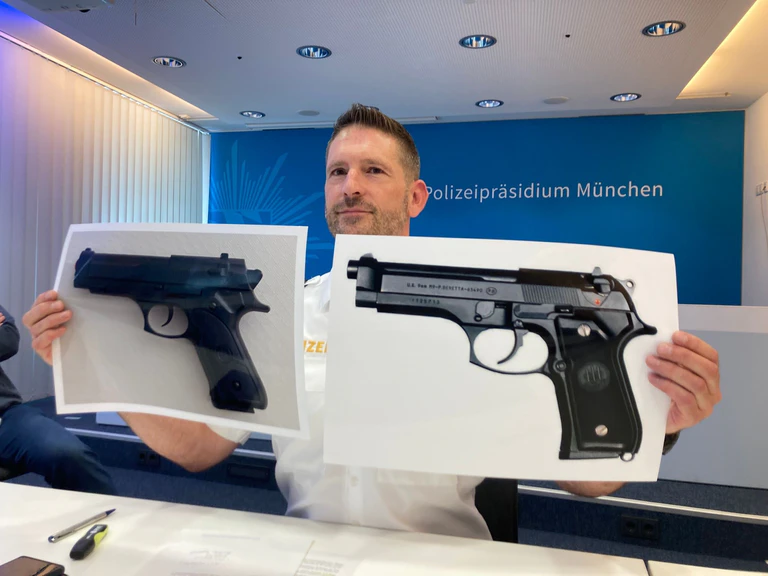Polizeisprecher Thomas Schelshorn zeigt Fotos der Softair-Waffe und der echten Waffe. — © Sabine Dobel/dpa