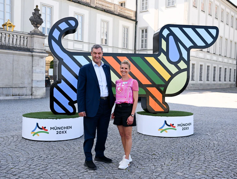 Ein riesiger Werbedackel mit Bayerns Ministerpräsident Markus Söder (CSU/l) und Olympiasiegerin Jessica von Bredlow-Werndl. (Archivbild) — © Sven Hoppe/dpa