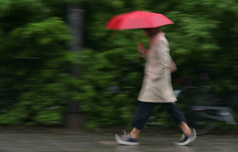 Regenschirm statt Sonnencreme - nach sonnigen Tagen nun nasses Regenwetter.  — © Malin Wunderlich/dpa