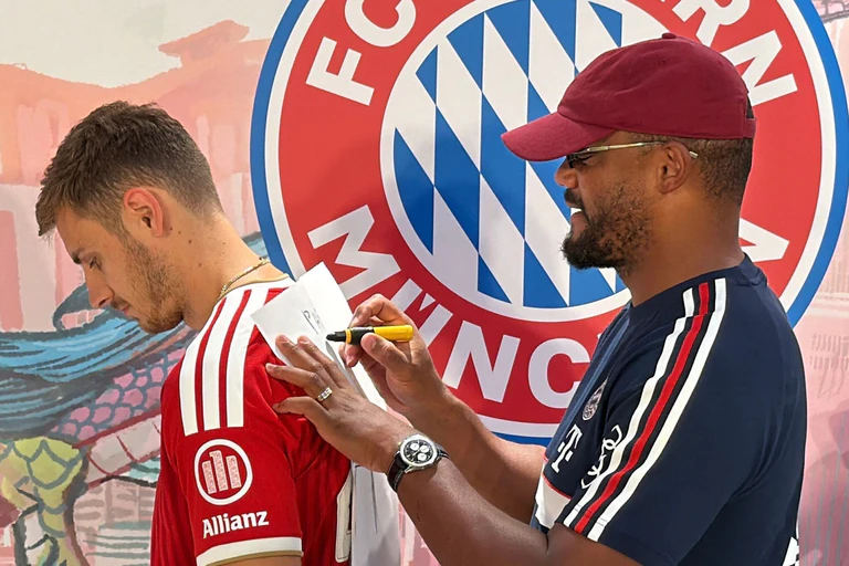Trainer Vincent Kompany (r) malt - und Josip Stanisic muss raten. — © Christian Kunz/dpa