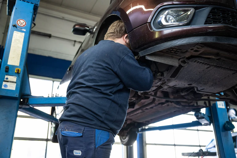 Ein Mechaniker schaut in einer Kfz-Werkstatt in den Radkasten eines Autos. — © Hannes P. Albert/dpa