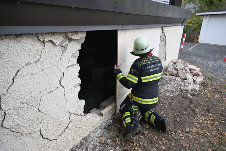 Ein Feuerwehrmann deckt das Loch in der Garagenwand ab. — © Felix Hörhager/dpa